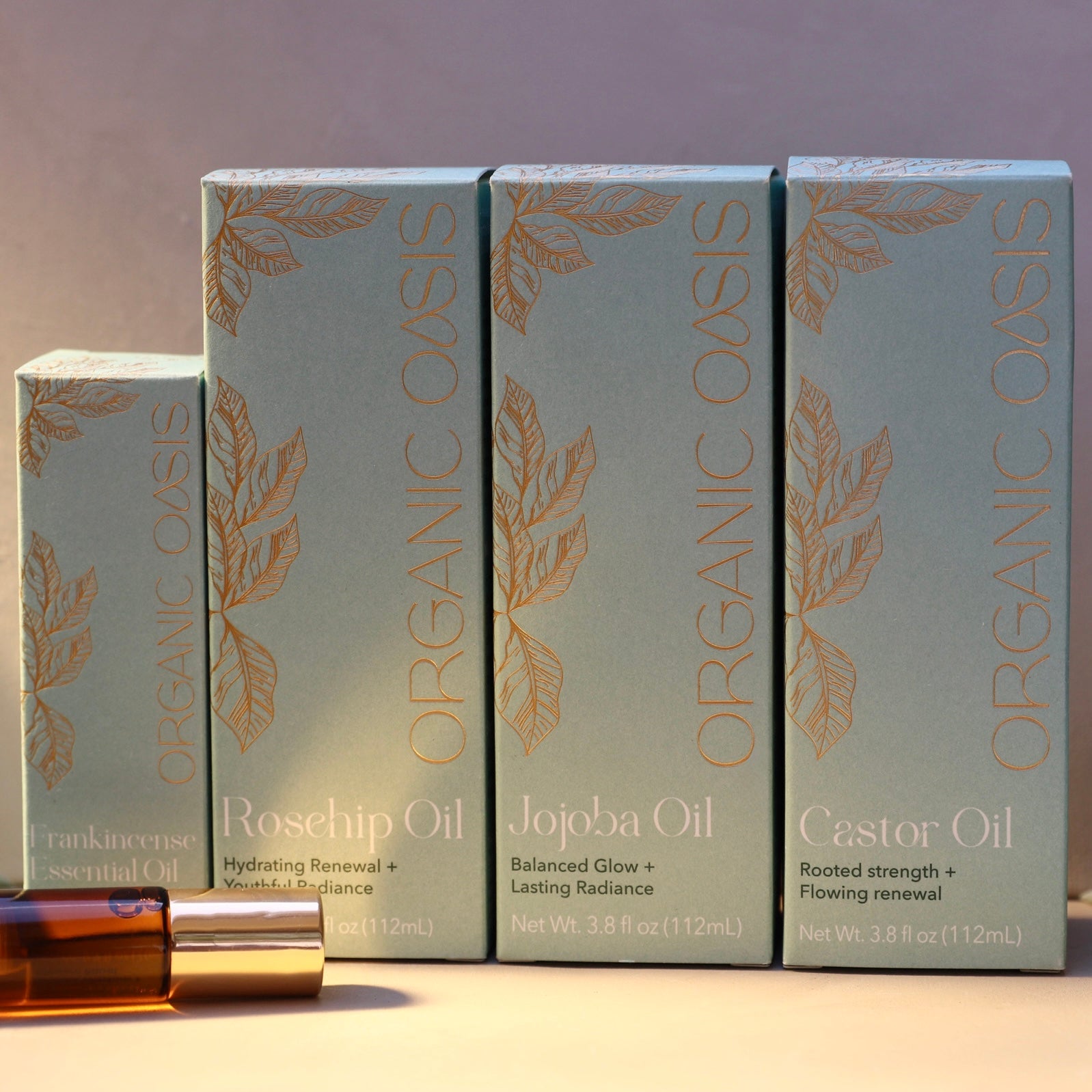 Four boxes of Organic Oasis essential oils on a wooden surface with a gradient background.