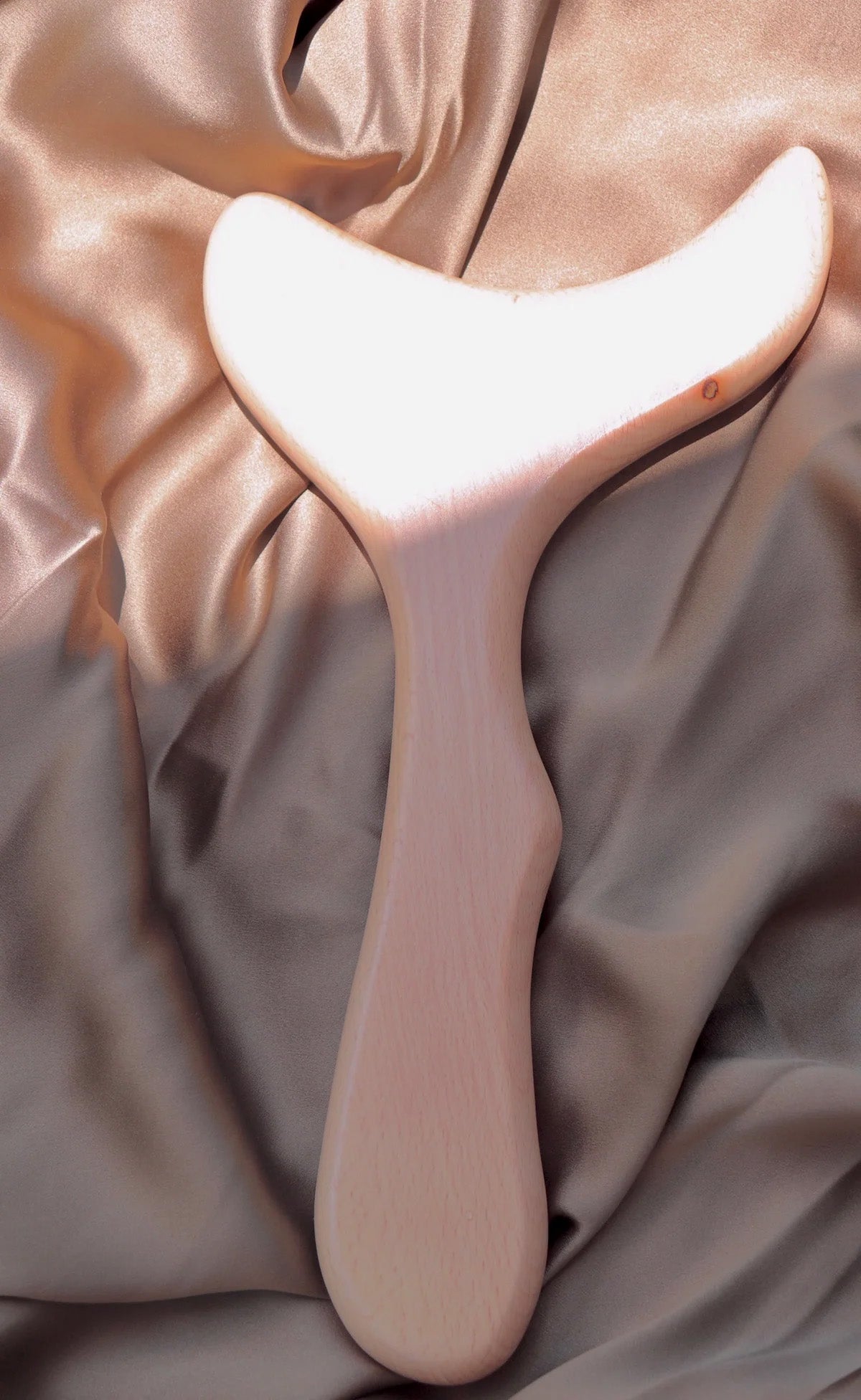 Body gua sha tool held against the skin