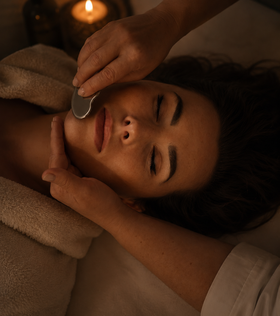 Person receiving a facial treatment with a candle in the background