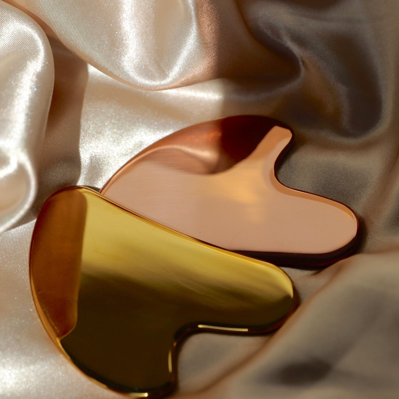 Gold stainless steel gua sha tool on satin
