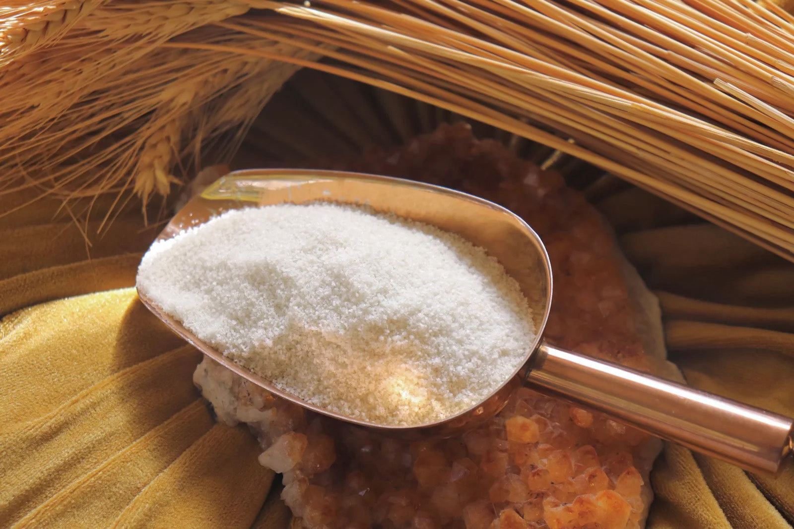 Scoop of white powder on a wooden surface with straw-like material in the background