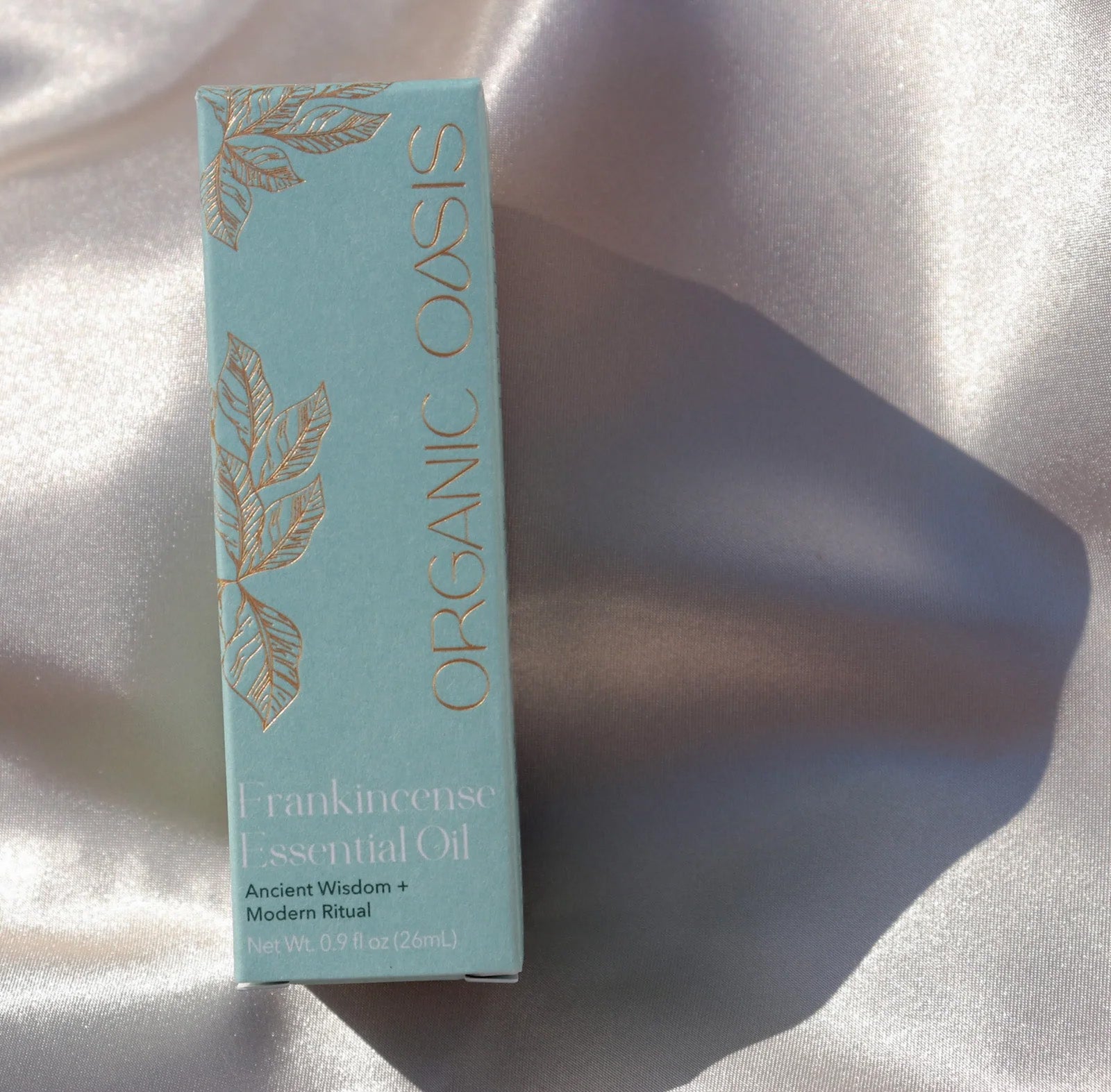 Organic Frankincense Essential Oil product packaging on silk fabric