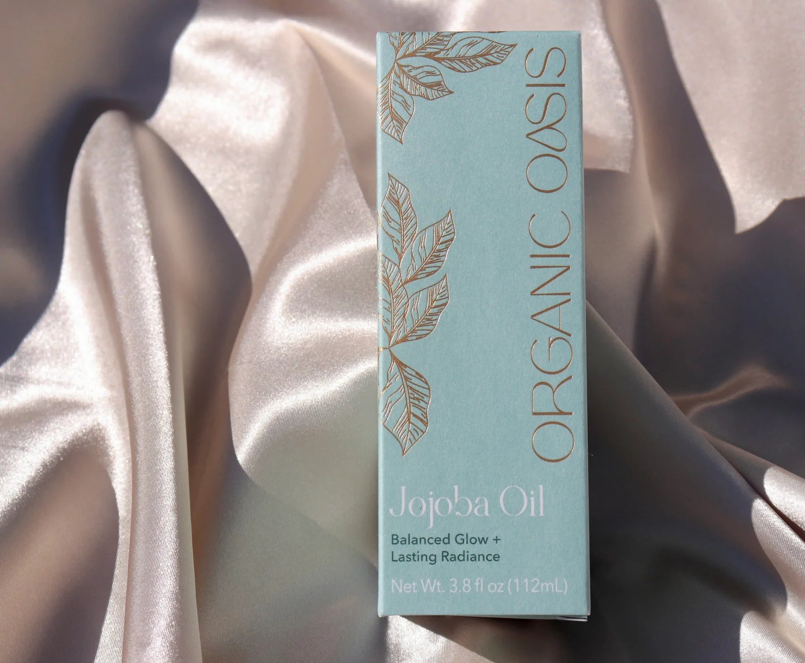 Organic Golden Jojoba Oil packaging on silk fabric