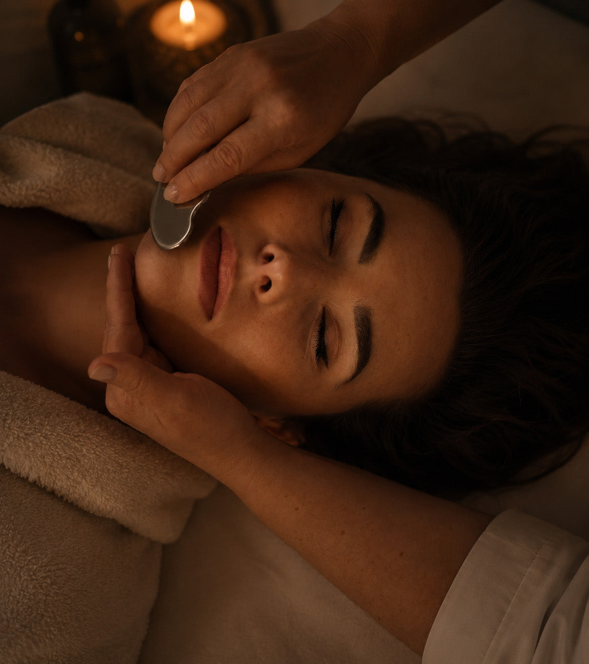 Person receiving a facial treatment with a candle in the background